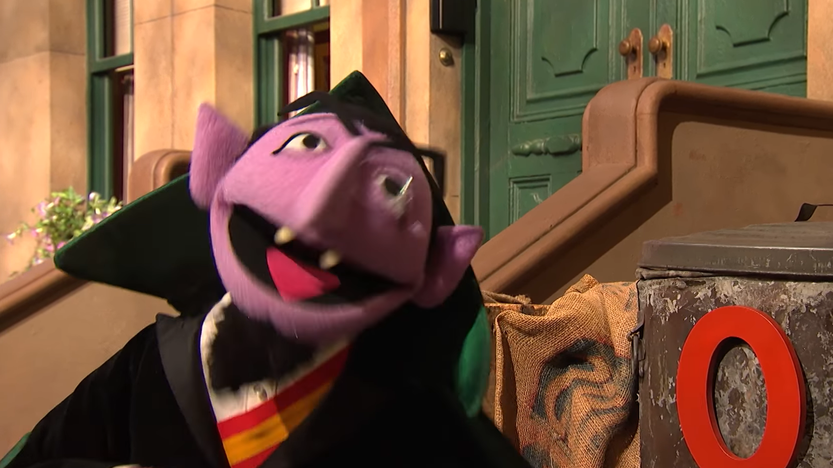 A puppet from a popular children's TV show with purple skin, a monocle, and a cape